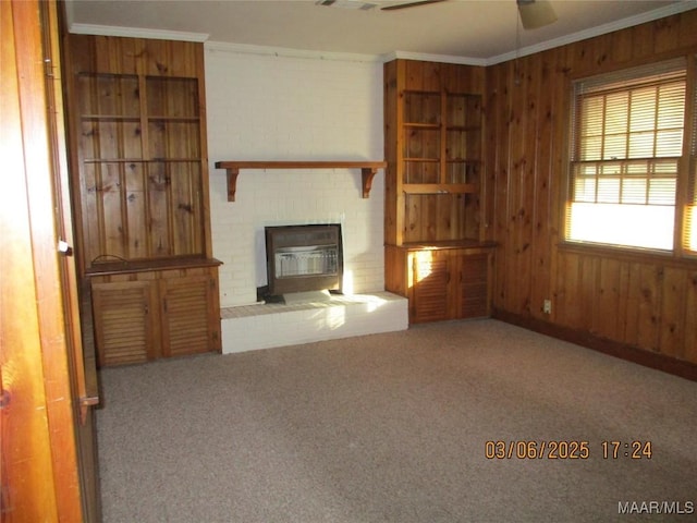 unfurnished living room featuring carpet flooring, wooden walls, a fireplace, and crown molding