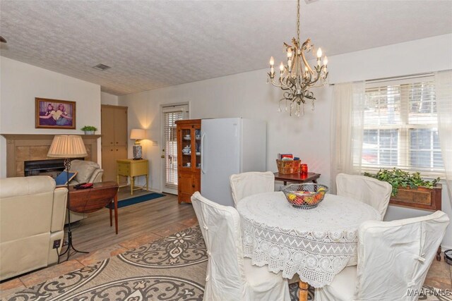 100 Royal Dr, Equality, AL 36026 - dining room featuring a chandelier, visible vents, a tiled fireplace, and a textured ceiling