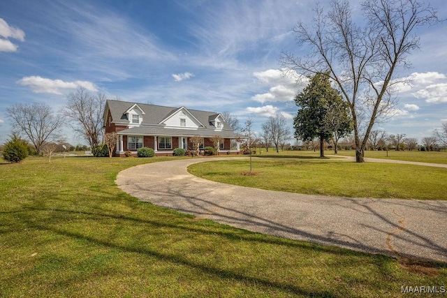cape cod home featuring a front lawn, a porch, brick siding, and curved driveway