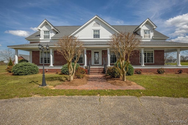 country-style home with brick siding, a porch, a shingled roof, and a front lawn