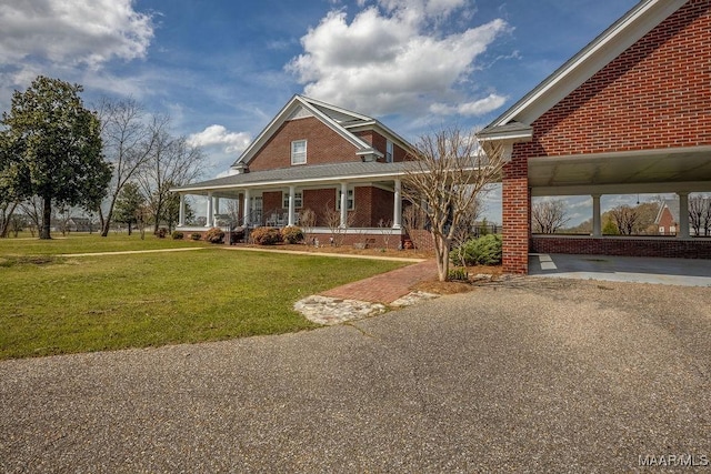 country-style home featuring a front yard, a porch, brick siding, and driveway