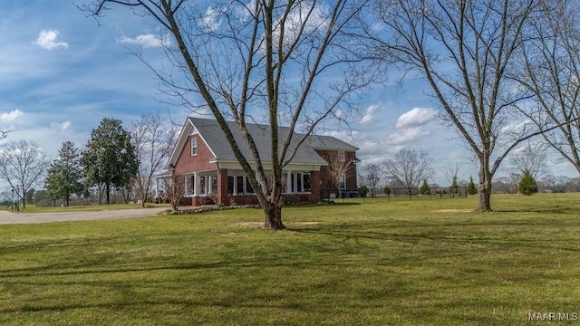 view of front of house featuring brick siding, driveway, a front lawn, and fence