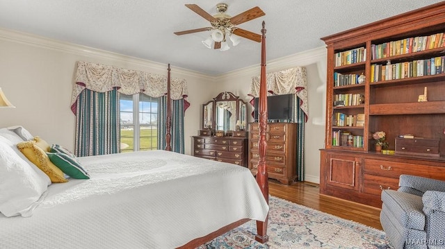 bedroom featuring a textured ceiling, wood finished floors, a ceiling fan, and ornamental molding