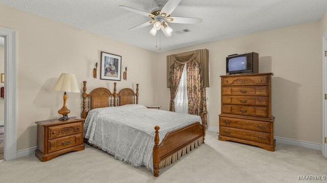 bedroom with visible vents, baseboards, light colored carpet, and a textured ceiling