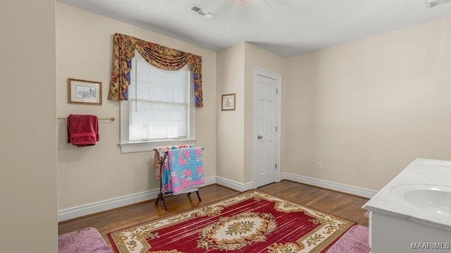 bathroom with visible vents, wood finished floors, baseboards, and a textured ceiling