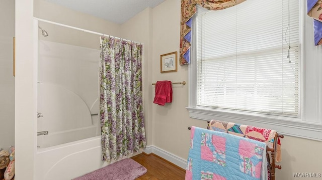bathroom with baseboards, wood finished floors, and shower / bath combination with curtain