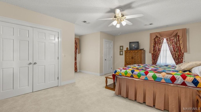 bedroom with light carpet, visible vents, a textured ceiling, and a closet