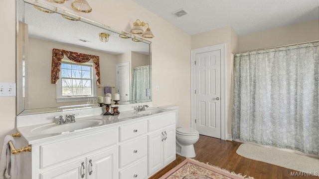 bathroom with double vanity, visible vents, wood finished floors, and a sink