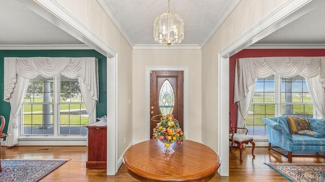 entrance foyer featuring a textured ceiling, crown molding, wood finished floors, and a chandelier