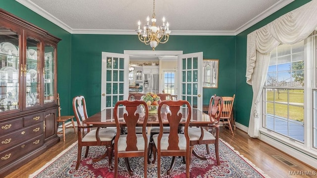 dining area with french doors, an inviting chandelier, wood finished floors, and visible vents