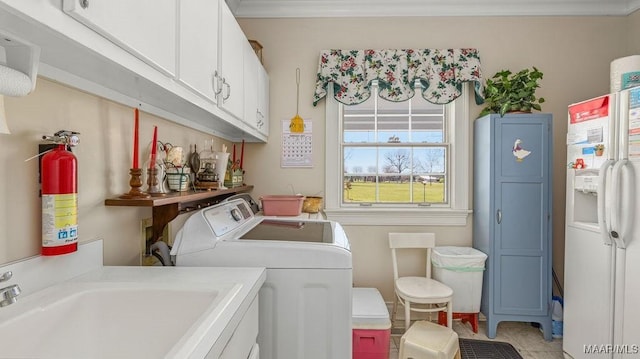 laundry area with cabinet space, ornamental molding, separate washer and dryer, and a sink