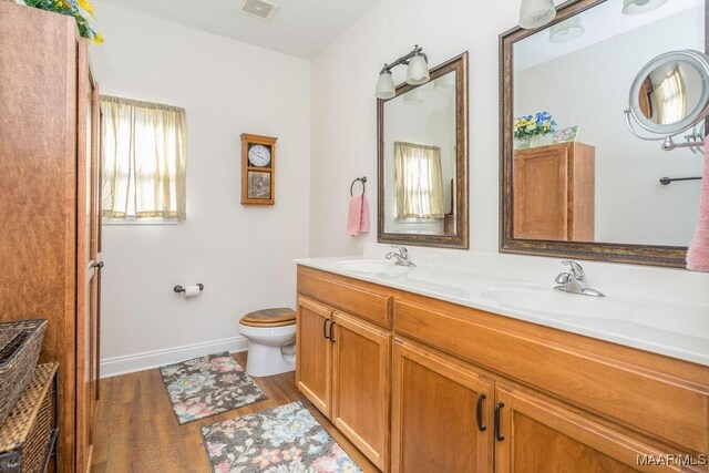bathroom with toilet, wood finished floors, visible vents, and a sink