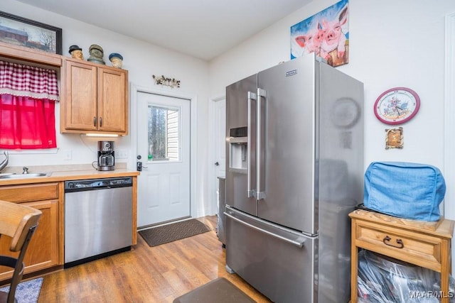 kitchen featuring a sink, stainless steel appliances, light wood-style floors, and light countertops