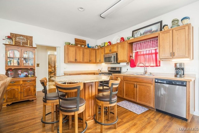 kitchen with a breakfast bar, dark wood finished floors, a sink, stainless steel appliances, and a center island