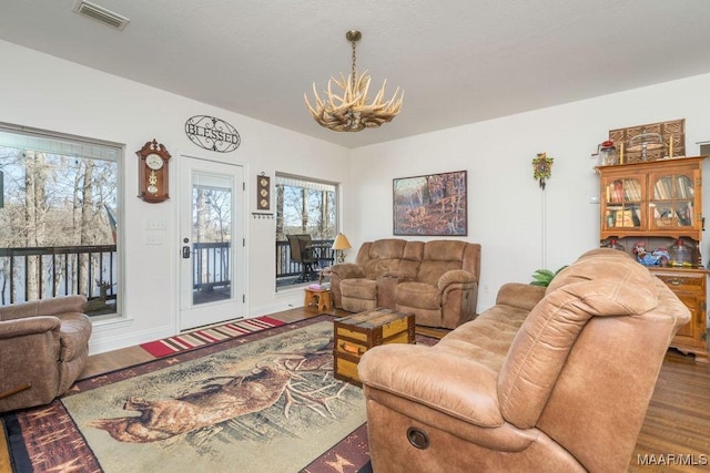 living area featuring a chandelier, visible vents, baseboards, and wood finished floors