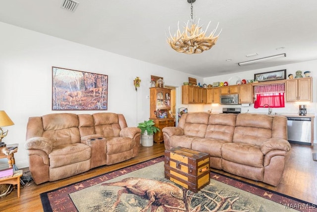 living area with visible vents, light wood finished floors, and a chandelier