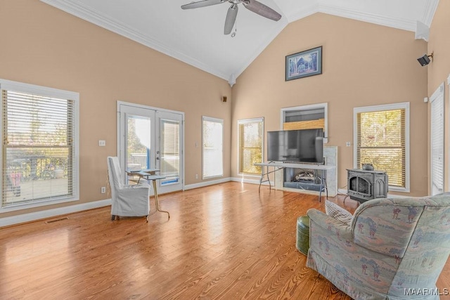 living room with visible vents, a ceiling fan, wood finished floors, french doors, and a wood stove