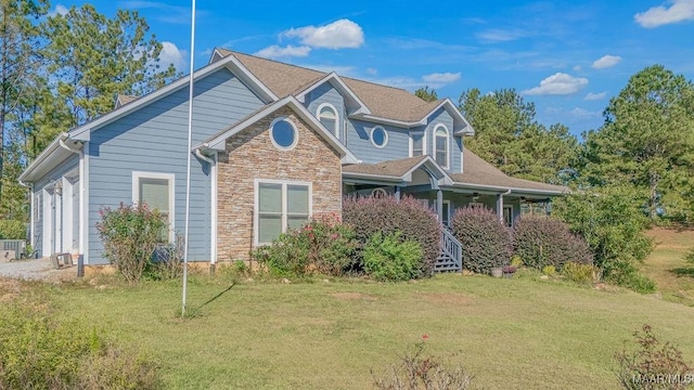 view of front facade with stone siding and a front lawn