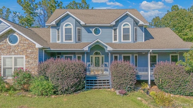 view of front facade featuring covered porch, stone siding, and roof with shingles