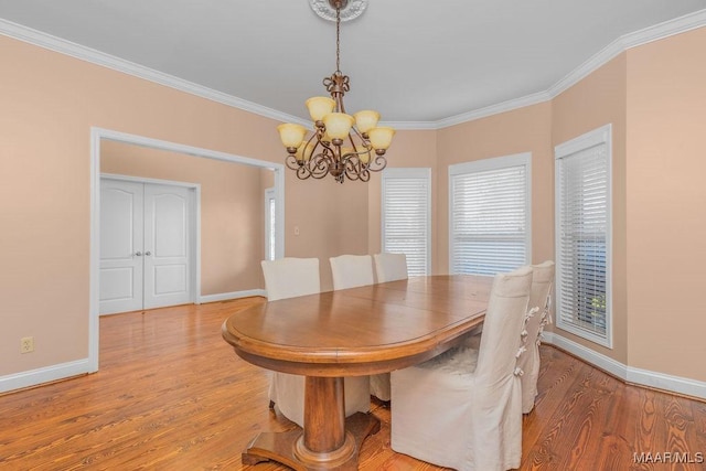 dining area with baseboards, an inviting chandelier, wood finished floors, and crown molding