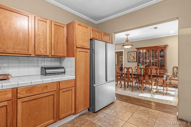 212 N Taylor St, Autaugaville, AL 36067 - kitchen with visible vents, backsplash, crown molding, light tile patterned floors, and freestanding refrigerator