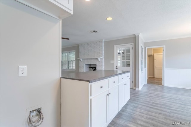 3740 Fieldcrest Dr, Montgomery, AL 36111 - kitchen with crown molding, white cabinetry, a fireplace, light wood-type flooring, and open floor plan