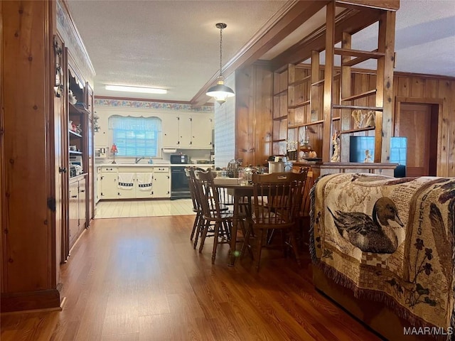 89 First Ave, Luverne, AL 36049 - dining space featuring crown molding, wood walls, light wood-type flooring, and a textured ceiling