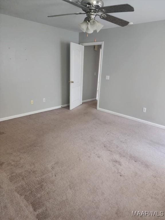 carpeted spare room featuring baseboards and ceiling fan