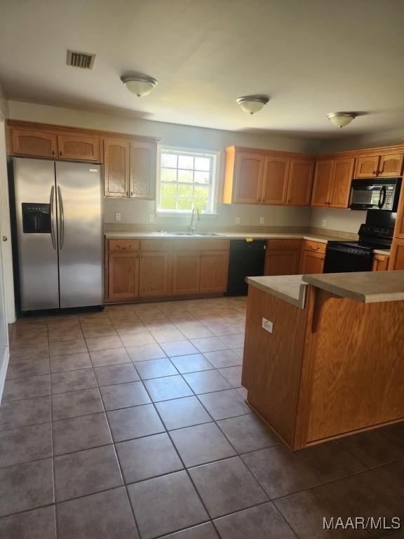 kitchen with tile patterned floors, light countertops, a sink, visible vents, and black appliances
