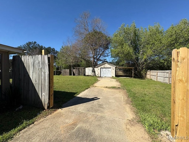 view of yard with an outbuilding, a garage, concrete driveway, and fence