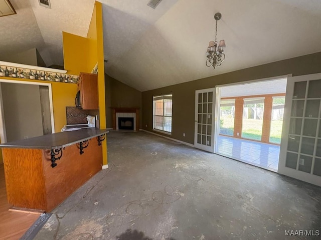 unfurnished living room with visible vents, a fireplace, an inviting chandelier, concrete flooring, and vaulted ceiling