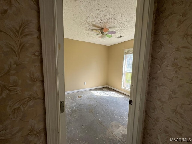 unfurnished room featuring a ceiling fan, a textured ceiling, baseboards, and visible vents