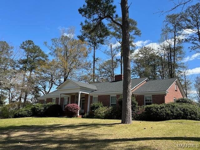 view of front of property with a chimney and a front lawn