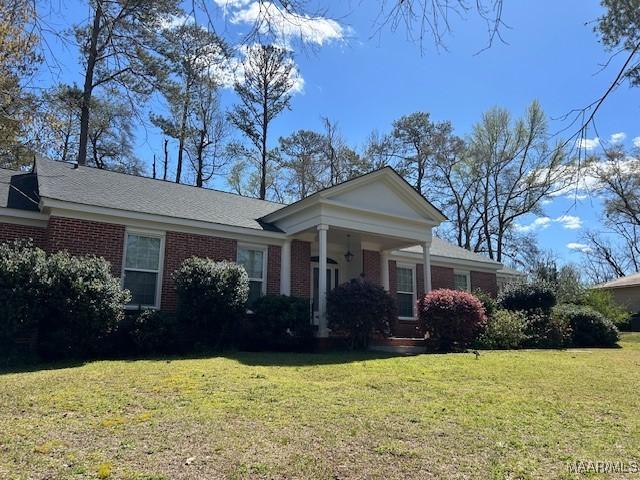 neoclassical home featuring brick siding and a front lawn
