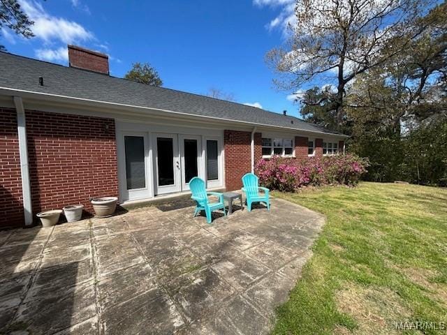 back of property featuring brick siding, a patio area, and a lawn