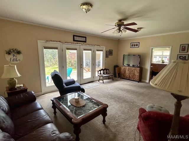 carpeted living area with french doors, a ceiling fan, crown molding, and baseboards