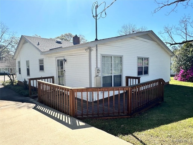 back of house with a chimney, a deck, and a yard