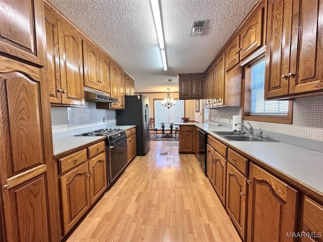 kitchen featuring visible vents, a chandelier, under cabinet range hood, a sink, and black appliances
