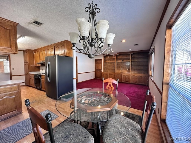 dining space featuring a notable chandelier, a textured ceiling, light wood finished floors, and visible vents