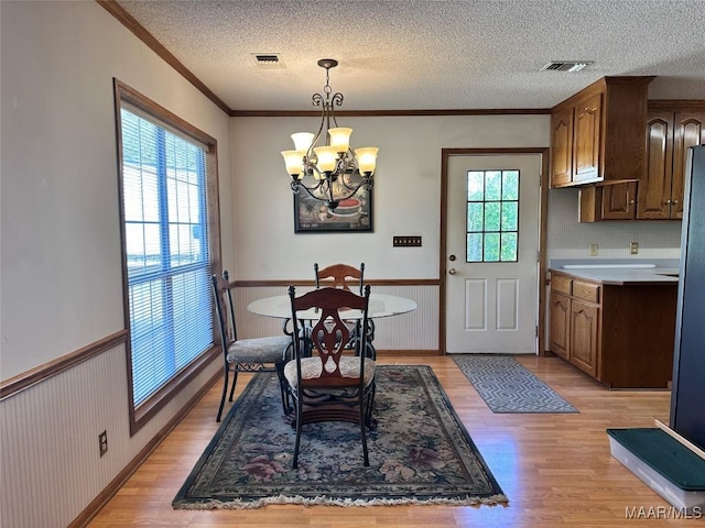 dining room featuring a notable chandelier, visible vents, and wainscoting
