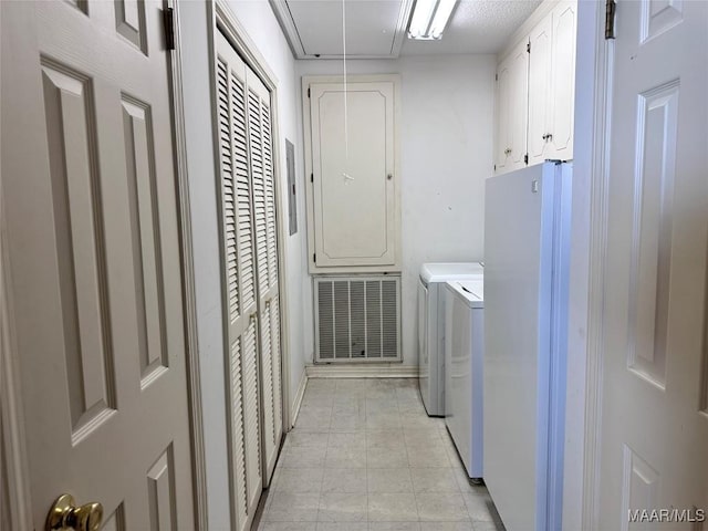 clothes washing area with washer and clothes dryer, cabinet space, and attic access