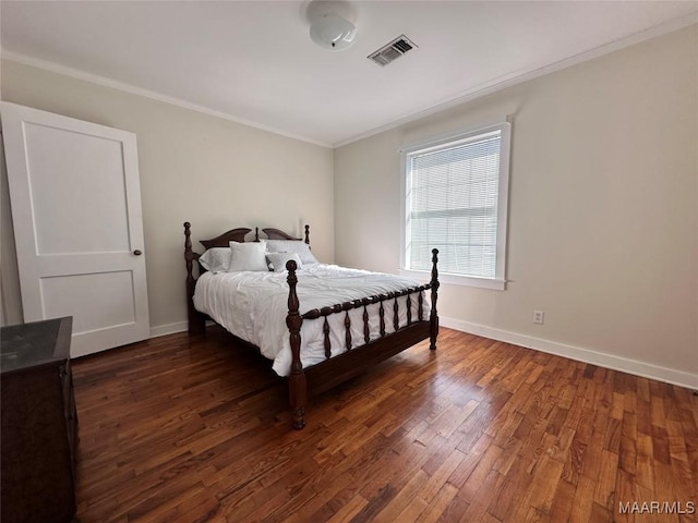 bedroom with baseboards, visible vents, crown molding, and wood finished floors