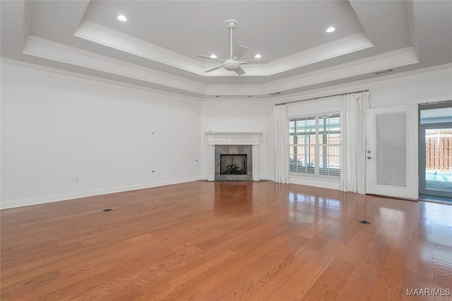 1580 W Overbrook Rd, Millbrook, AL 36054 - unfurnished living room with wood finished floors, crown molding, a ceiling fan, a tray ceiling, and a tiled fireplace