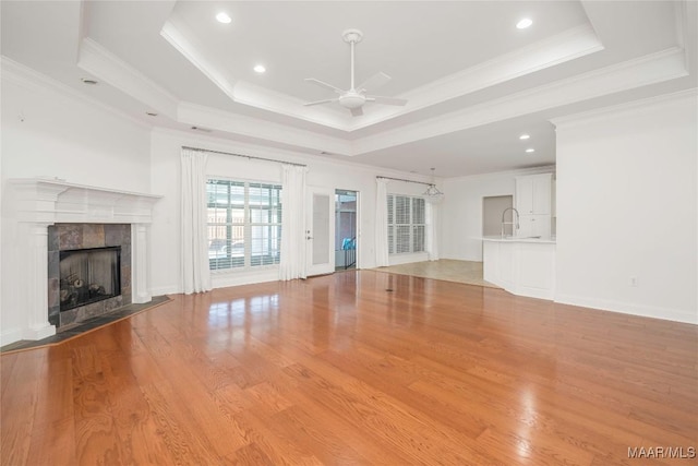 1580 W Overbrook Rd, Millbrook, AL 36054 - unfurnished living room with light wood-style flooring, a ceiling fan, a tray ceiling, a fireplace, and ornamental molding