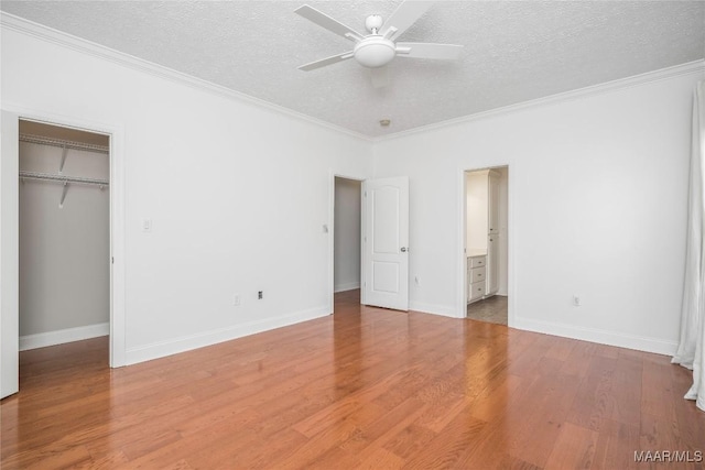1580 W Overbrook Rd, Millbrook, AL 36054 - unfurnished bedroom with a closet, a walk in closet, crown molding, a textured ceiling, and light wood-style floors