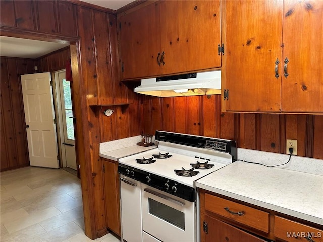 125 Butler St, Selma, AL 36701 - kitchen with wood walls, white gas range oven, under cabinet range hood, and light countertops