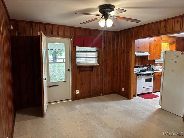 125 Butler St, Selma, AL 36701 - kitchen featuring under cabinet range hood, ceiling fan, brown cabinetry, wood walls, and white appliances