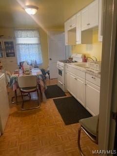 kitchen featuring white cabinetry, light countertops, white range with gas stovetop, and a sink