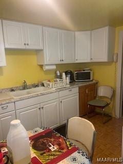 kitchen with a sink, light countertops, white cabinets, and stainless steel microwave