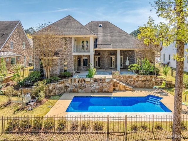 9533 Fendall Hall Cir, Montgomery, AL 36117 - rear view of property featuring a balcony, a shingled roof, a fenced front yard, and a patio area